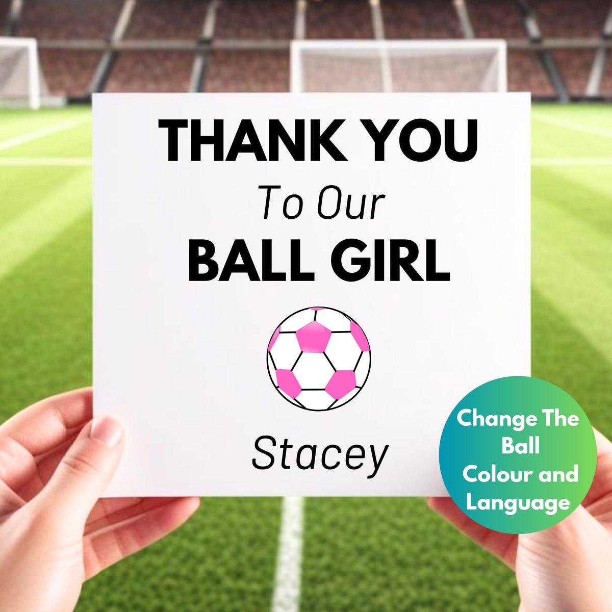 A person is holding a white thank you card in front of a background of a soccer field. The card says "Thank You to Our Ball Girl" with a green and white soccer ball graphic and the name "Stacey" as an example of a personalized name. There's a note indicating that customers can change the ball color and language.