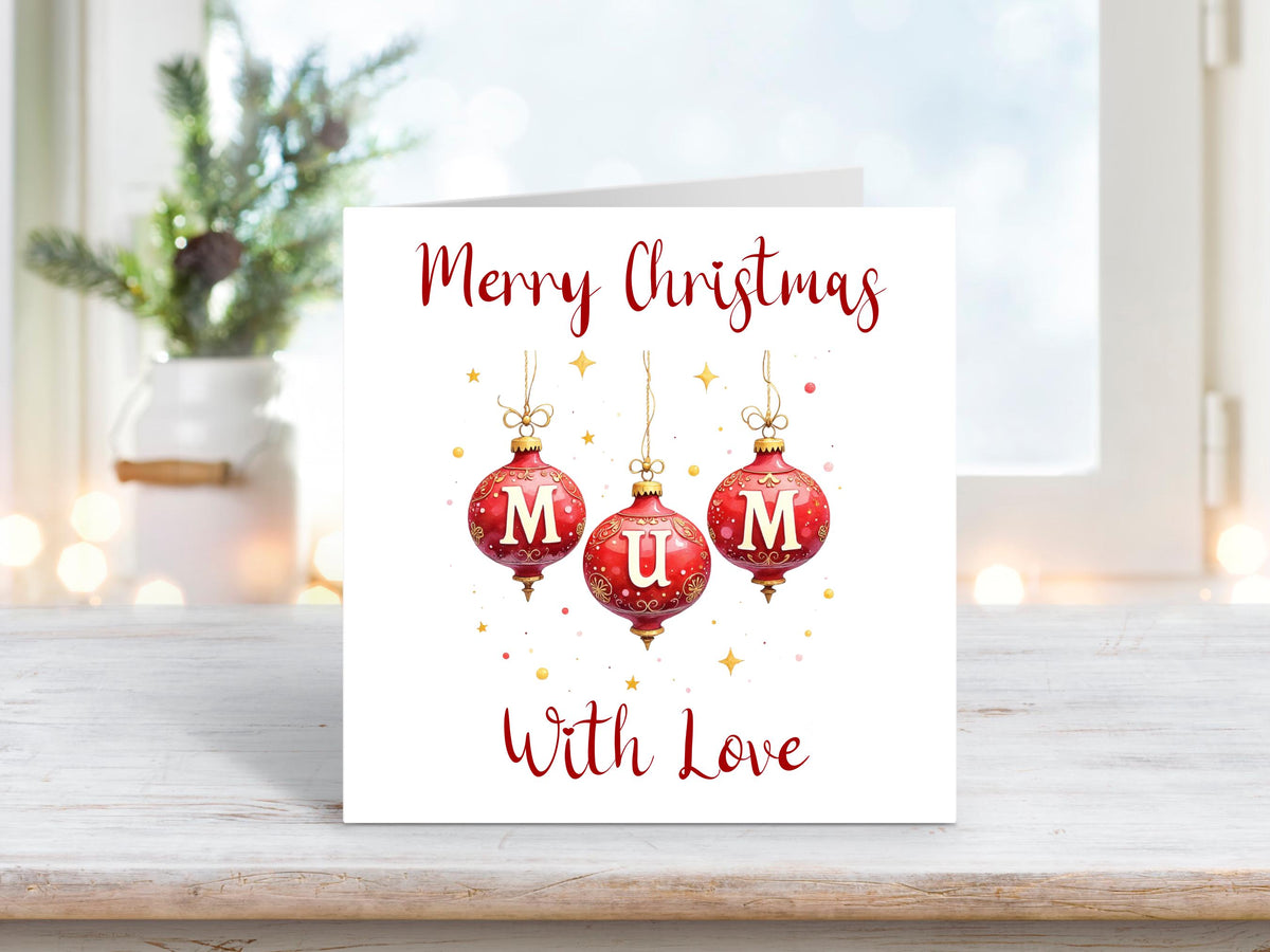 Christmas card featuring three red baubles spelling “MUM” with gold stars and text reading “Merry Christmas With Love” on a white background.