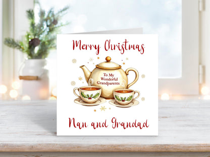 Christmas card featuring a festive teapot with the words “To My Wonderful Grandparents” and two holly-decorated teacups, surrounded by golden snowflakes, with “Merry Christmas Nan and Grandad” written above and below.