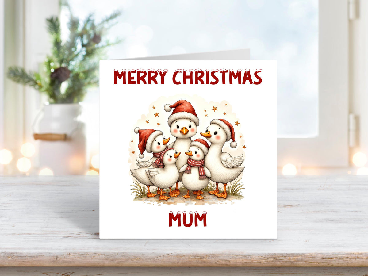 Personalised Christmas card showing a group of five white ducks wearing Santa hats and scarves, huddled together with stars in the background, and “Merry Christmas Mum” written above and below.