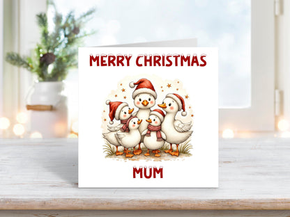 Personalised Christmas card showing a group of five white ducks wearing Santa hats and scarves, huddled together with stars in the background, and “Merry Christmas Mum” written above and below.