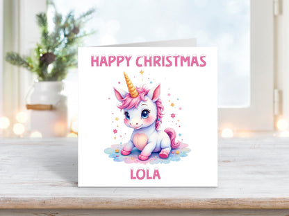 Personalised Christmas card featuring a cute pastel unicorn with pink mane and golden horn, surrounded by stars, with the name “Lola” and “Happy Christmas” in pink text.