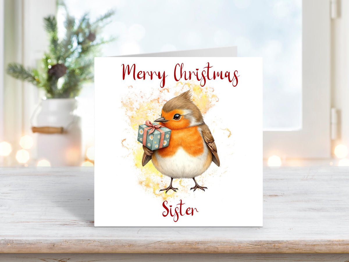 Christmas card for sister featuring a sweet robin holding a green gift on a soft yellow and orange background.