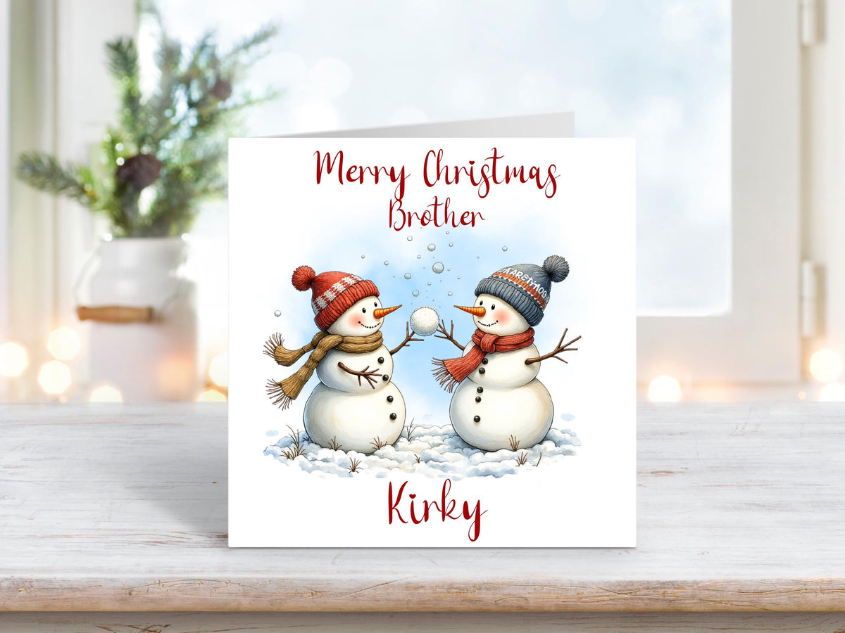 Festive card with two snowmen in woolly hats having a snowball fight, with “Merry Christmas Brother” text and personalised name “Kirky”.