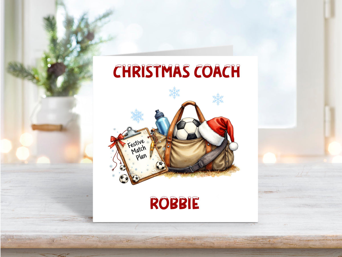 Christmas card featuring a festive football coach scene with a sports bag, Santa hat, clipboard titled “Festive Match Plan”, and football, personalised with the name Robbie.