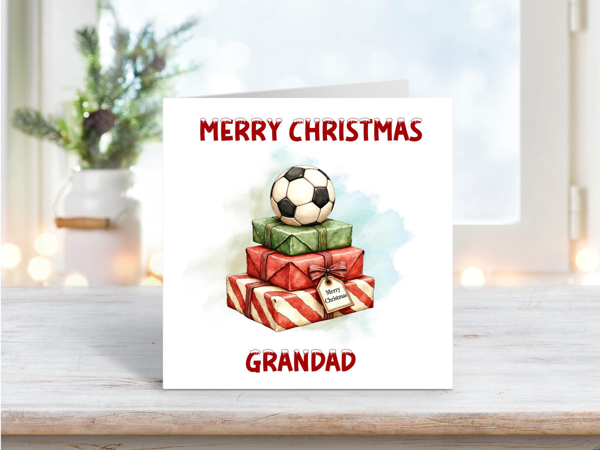Christmas card showing a stack of red and green presents topped with a football, personalised with “Grandad” and the words “Merry Christmas.”