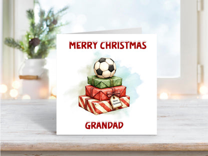Christmas card showing a stack of red and green presents topped with a football, personalised with “Grandad” and the words “Merry Christmas.”