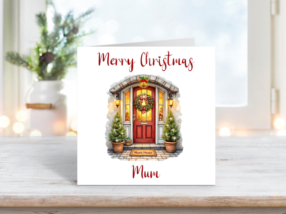 Christmas card featuring a red front door decorated with a wreath and potted Christmas trees, with the words “Merry Christmas Mum” above and below the image.