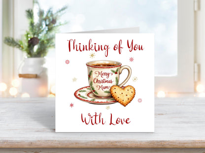 Christmas card featuring a festive teacup and saucer with “Merry Christmas Mum” written on it, and a heart-shaped biscuit beside it, with the words “Thinking of You With Love.”