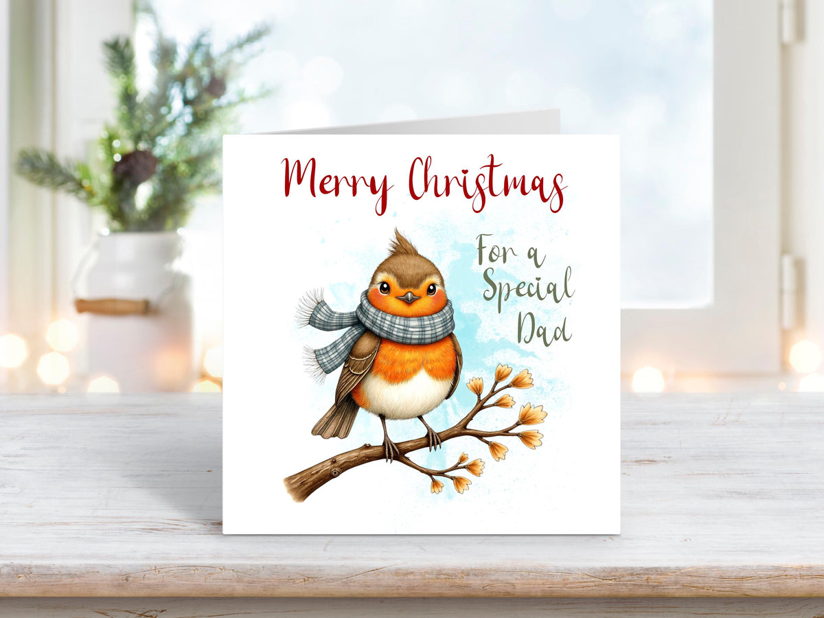 Christmas card featuring a robin wearing a grey scarf perched on a snowy branch, with the words “Merry Christmas For a Special Dad.”