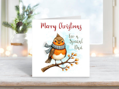 Christmas card featuring a robin wearing a grey scarf perched on a snowy branch, with the words “Merry Christmas For a Special Dad.”