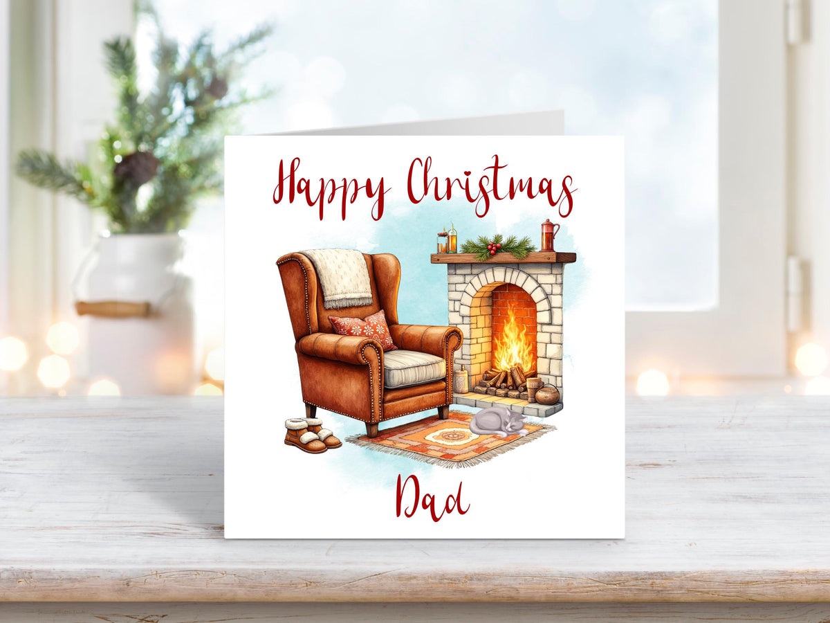 Christmas card featuring a cosy fireside scene with a leather armchair, slippers, and a roaring fire, with the words “Happy Christmas Dad.”