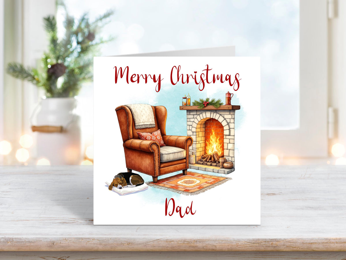 Christmas card featuring a cosy fireside scene with a leather armchair, roaring fire, and a dog sleeping on a blanket, with the words “Merry Christmas Dad.”