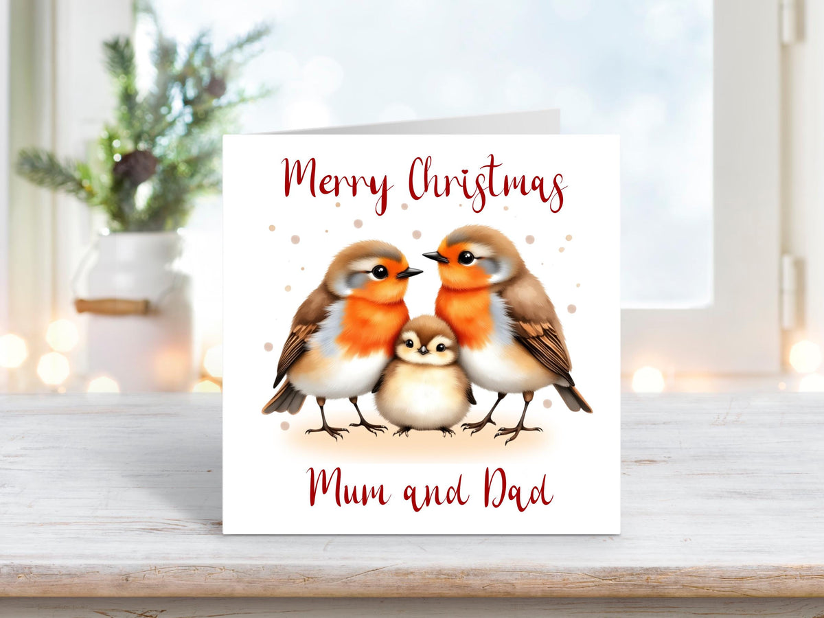 Christmas card featuring two robins with a baby robin between them, symbolising family and togetherness, with the words “Merry Christmas Mum and Dad.”