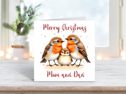 Christmas card featuring two robins with a baby robin between them, symbolising family and togetherness, with the words “Merry Christmas Mum and Dad.”