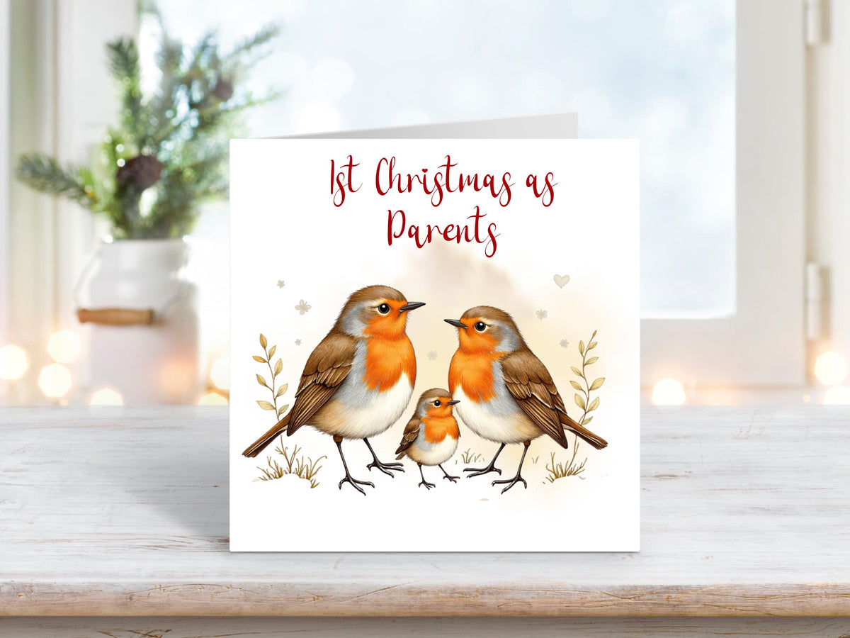 Christmas card featuring two adult robins and a baby robin standing together in a winter scene, with the words “1st Christmas as Parents.”