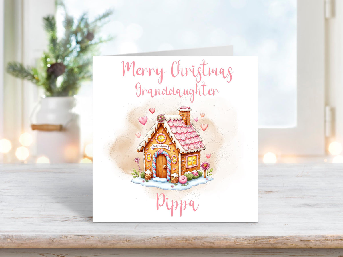 Personalised Christmas card for granddaughter featuring a pink gingerbread house with hearts on a white background