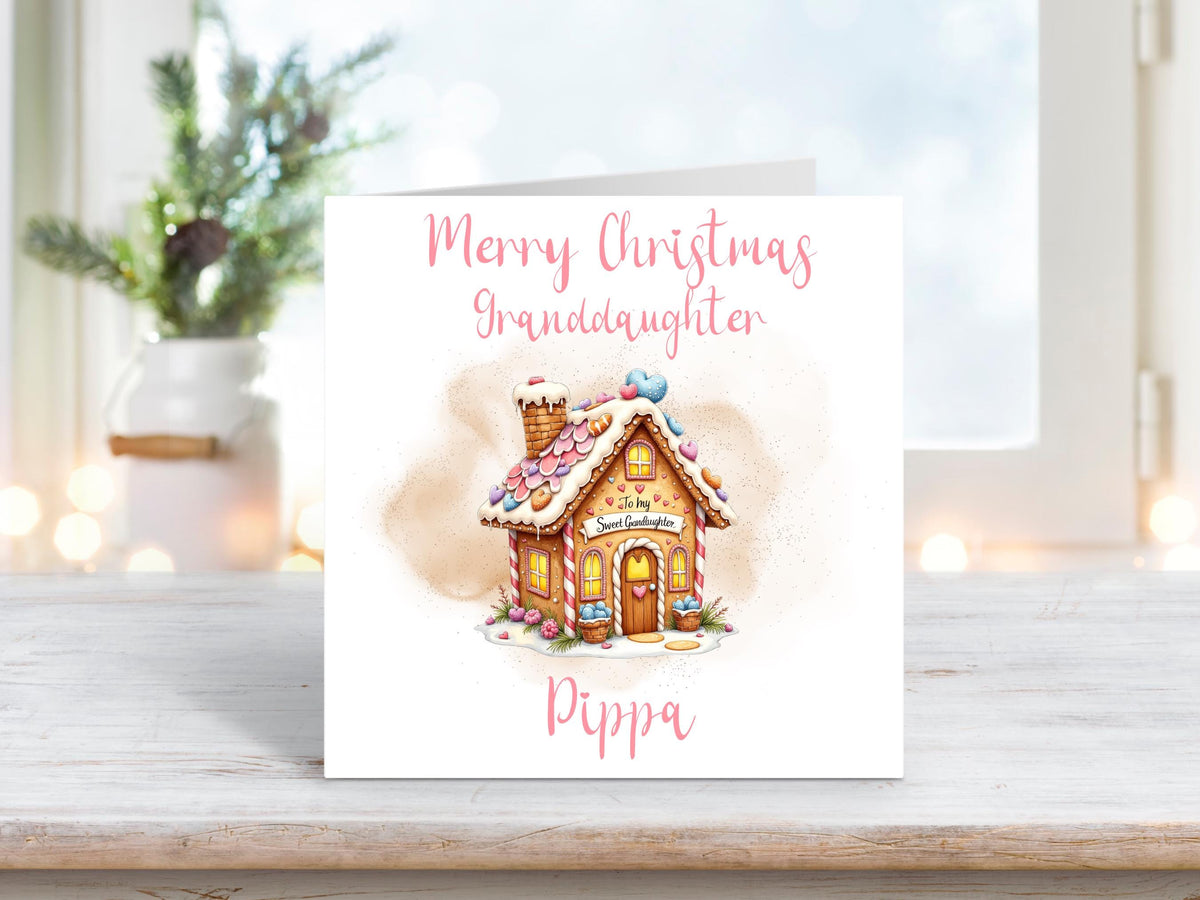 Personalised Christmas card for granddaughter featuring a pink gingerbread house with hearts on a white background