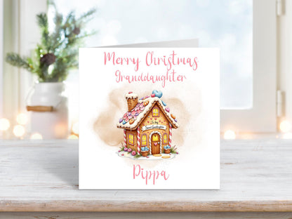 Personalised Christmas card for granddaughter featuring a pink gingerbread house with hearts on a white background
