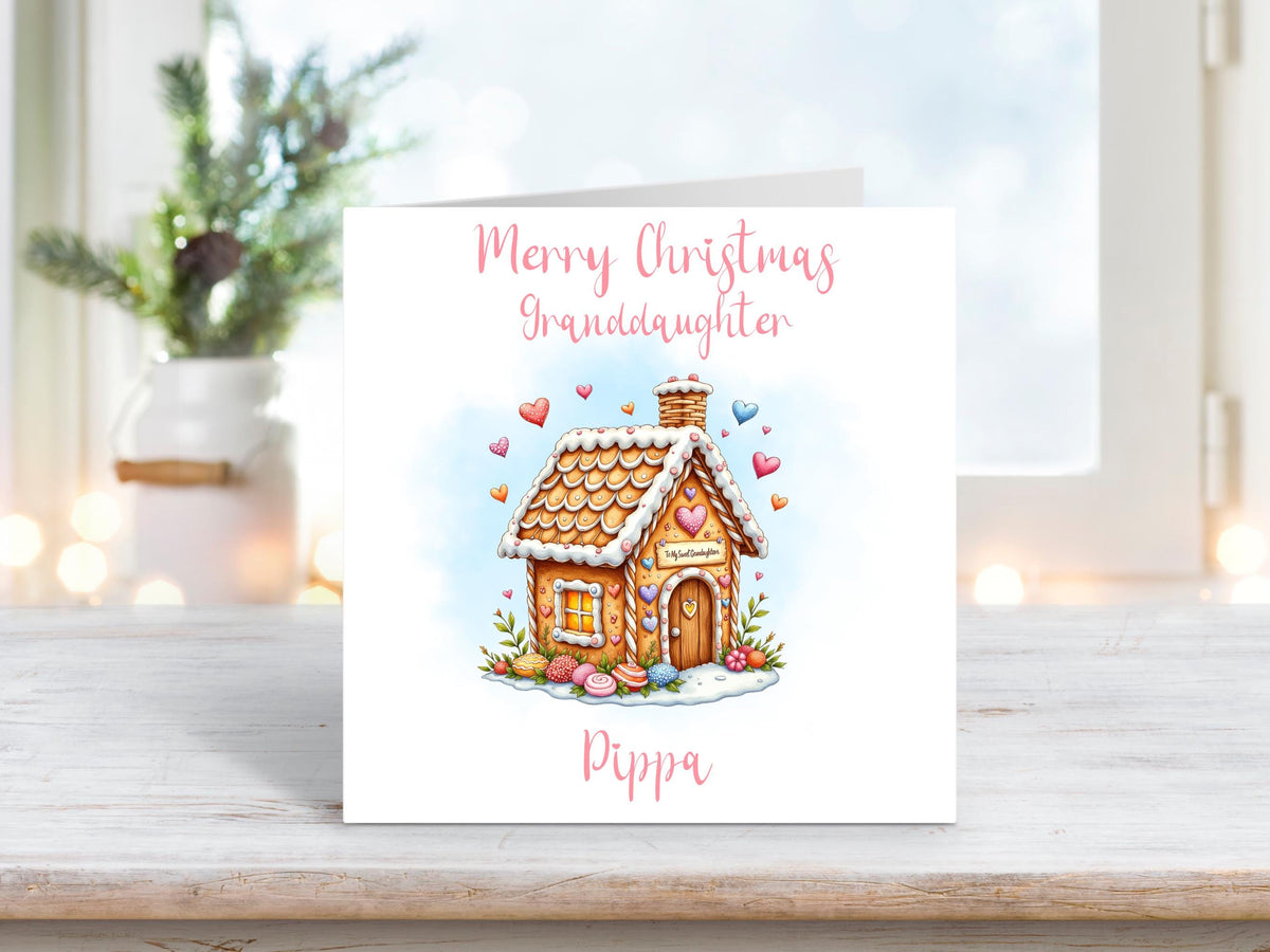 A sweet Christmas card for a granddaughter, featuring a pastel gingerbread house with heart decorations and personalised with her name.