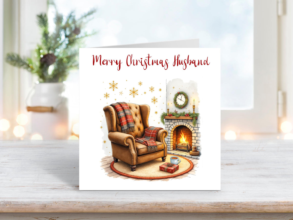 Christmas card for husband featuring a cosy armchair by a lit fireplace, with wrapped gifts, a mug, and festive decorations.