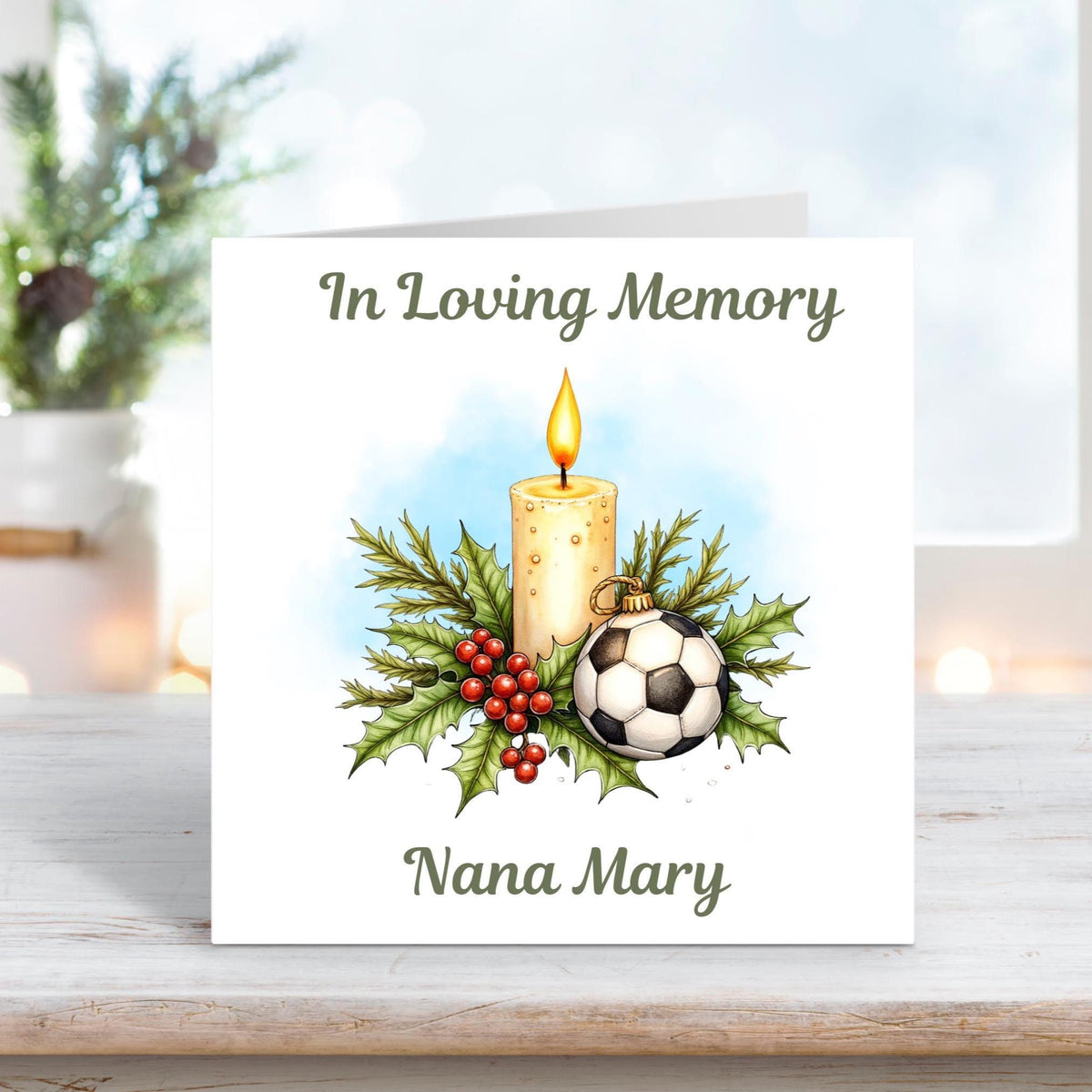 Memorial card with a glowing candle, holly, berries, and a football surrounded by greenery, with the text “In Loving Memory” and personalised name “Nana Mary.”