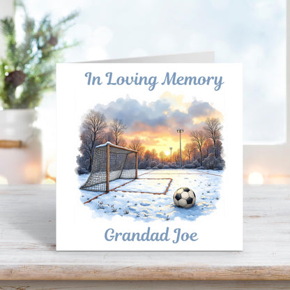 Memorial card featuring a football resting on a snowy pitch at sunrise, with the text “In Loving Memory” and personalised name “Grandad Joe.”