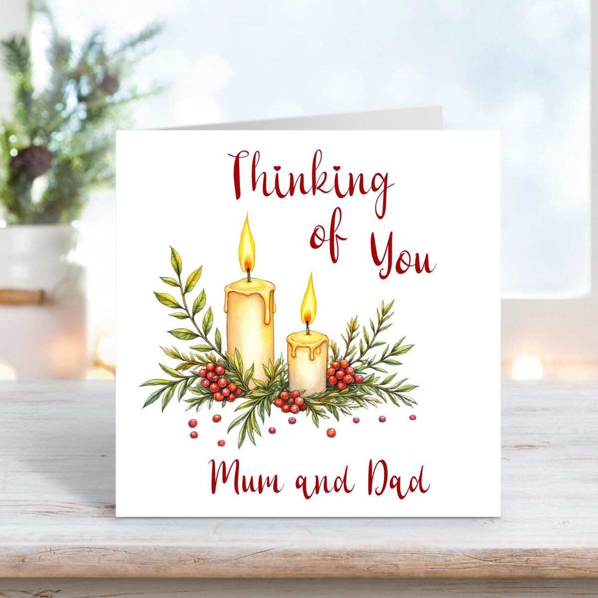 Christmas card featuring two glowing candles surrounded by holly, berries, and leaves, with the words “Thinking of You Mum and Dad” on a white background.