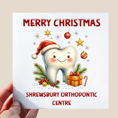 Smiling cartoon tooth wearing a Santa hat with festive decorations and space for any dentist or orthodontic practice name on a white background.