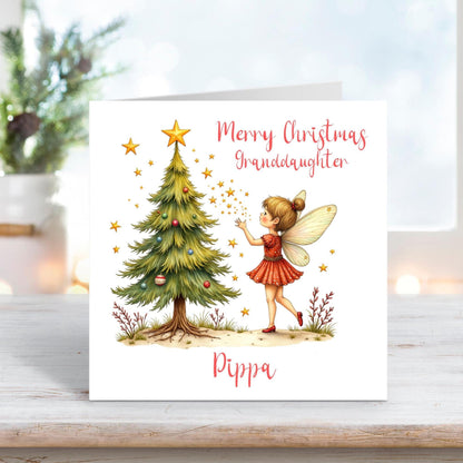 Personalised Christmas card for granddaughter featuring a fairy decorating a Christmas tree with stars on a white background