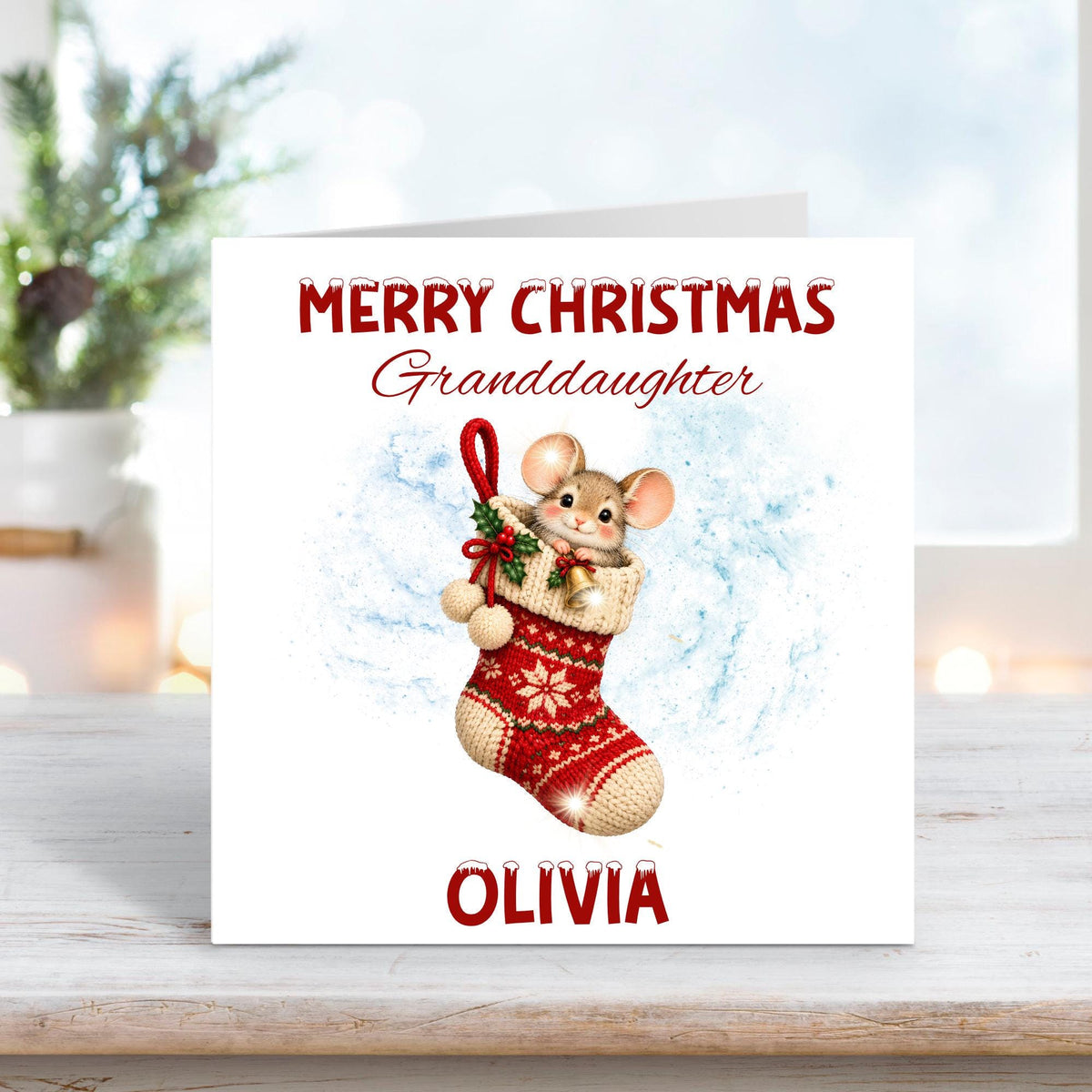 Personalised Merry Christmas Granddaughter card featuring an adorable little mouse peeking out of a red knitted Christmas stocking decorated with snowflakes, holly and bells. Custom name Olivia beneath the festive illustration.