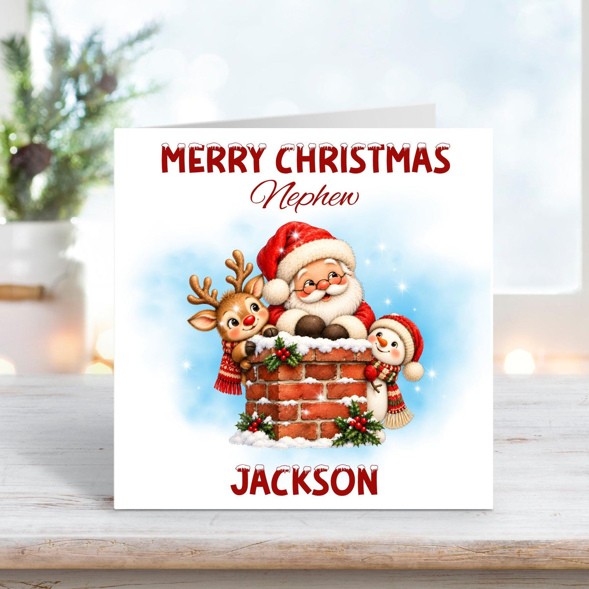 Personalised Merry Christmas Nephew card featuring a cheerful Santa Claus, cute reindeer and smiling snowman gathered around a snowy brick chimney decorated with holly and festive berries. Soft blue winter background with custom name Jackson.