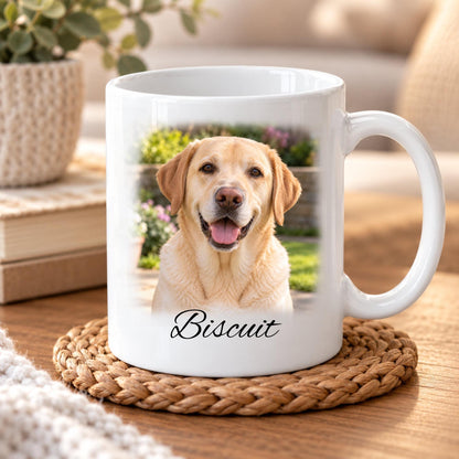 Personalised white ceramic photo mug featuring a golden Labrador retriever portrait with softly faded edges blending into the mug. Custom pet name Biscuit printed beneath the photograph in elegant black script lettering. Presented on a wooden table in a cosy home setting.