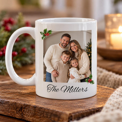 Personalised Christmas family photo mug featuring a rectangular photograph with clean straight edges, festive holly decorations and a custom family surname on a white ceramic mug.
